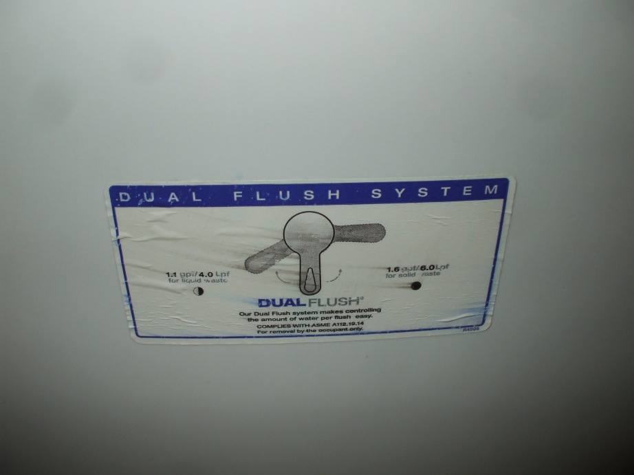 Sticker explaining a dual-flush toilet handle on the tank.