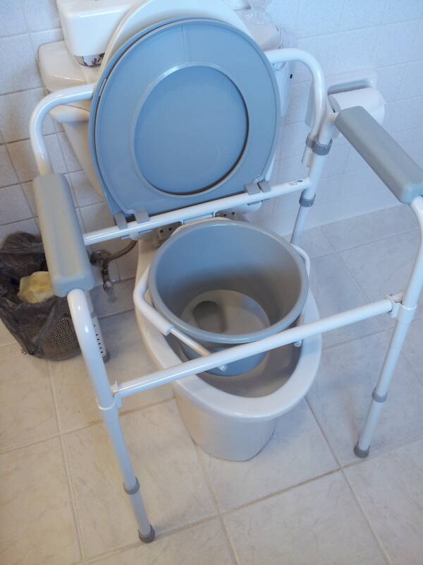 'Three-in-one' portable toilet unit placed over toilet.