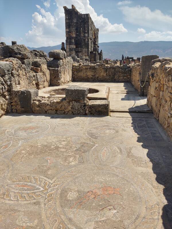 Triumphal arch and house with mosaic and basin at Volubilis.